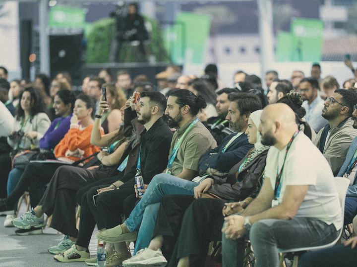 A packed conference audience listens to a session