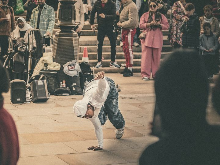 A crowd gathers on city steps to watch a street performer