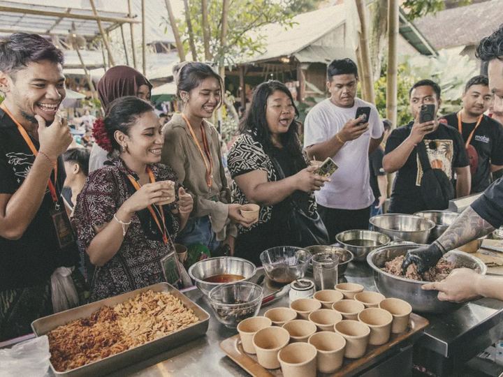 Guests film a chef's live demo at an outdoor food event