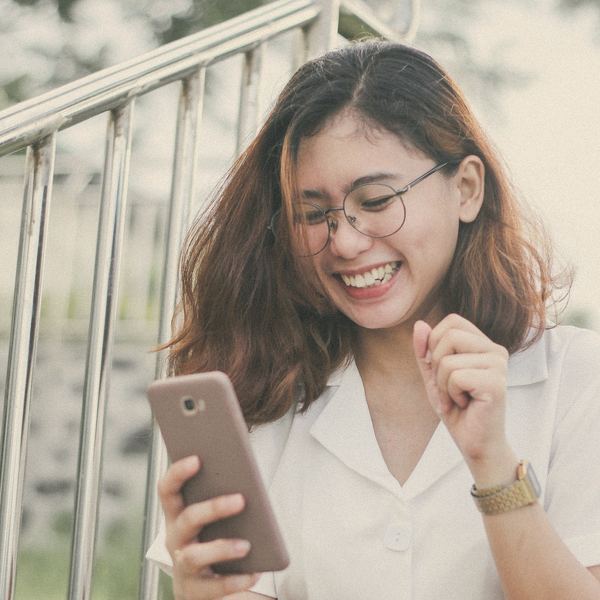 A woman laughs at something on her phone