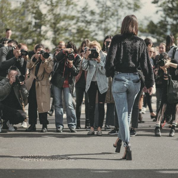 Photographers crowd a street to photograph a woman walking past