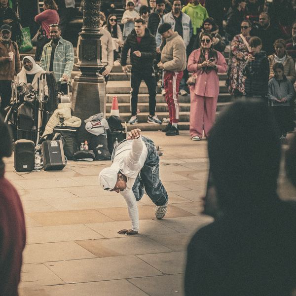 A crowd gathers on city steps to watch a street performer