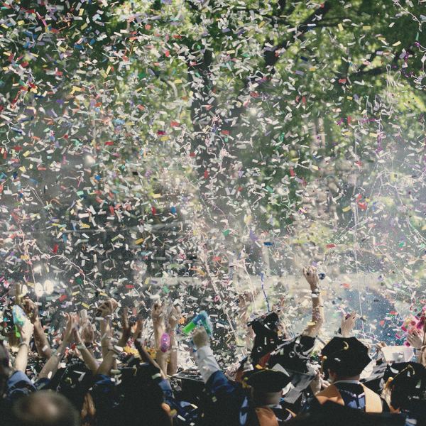 Confetti falls over a cheering outdoor crowd