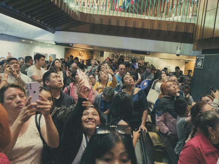 A crowd looks up in delight at an indoor event
