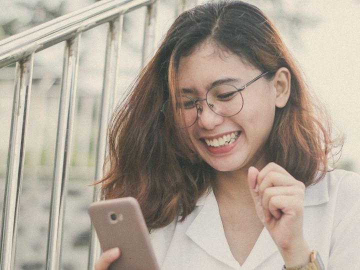 A woman laughs at something on her phone