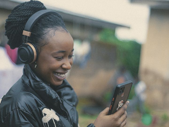 A woman smiles as she listens through headphones